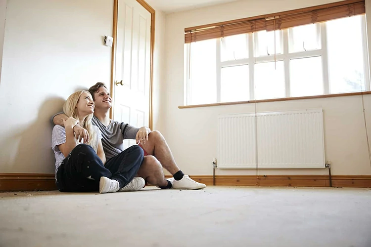 Couple Sitting On Floor In Empty Room Of New Home Planning Design