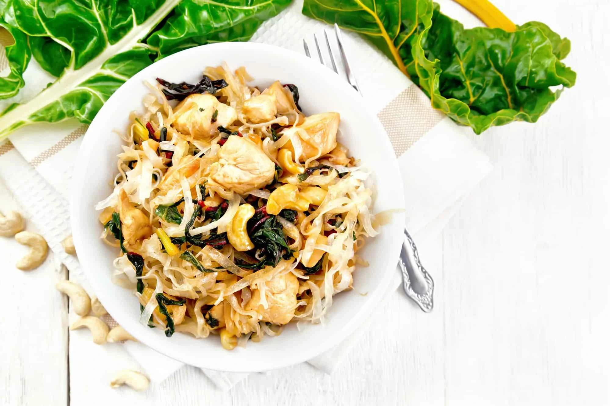 Funchoza with chard and cashew in bowl on board top