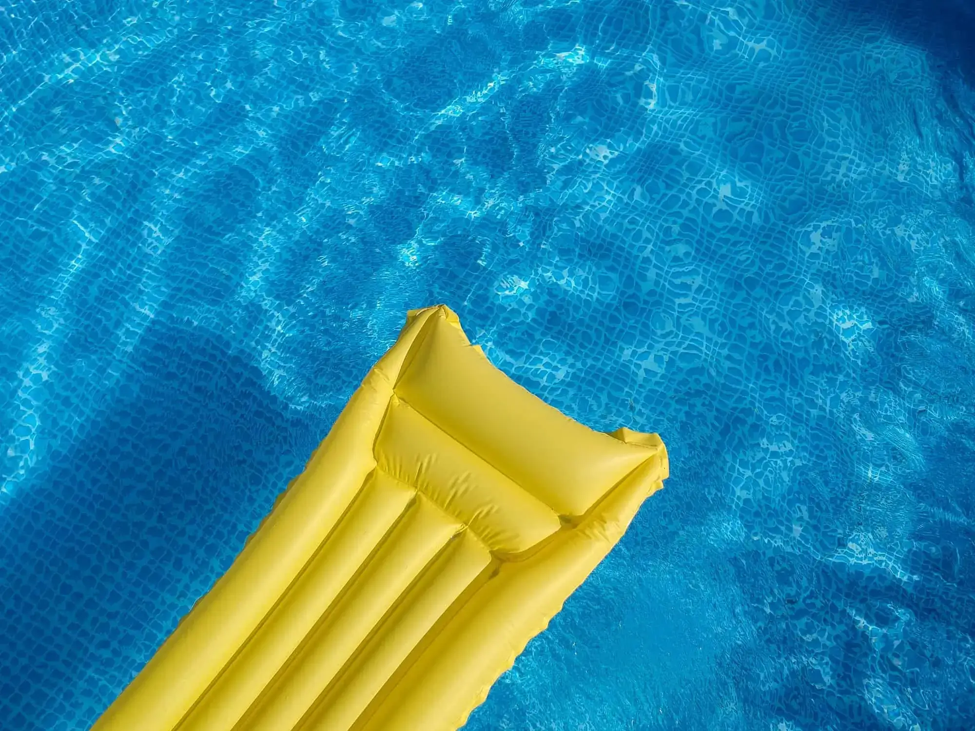 Top view of an inflatable mattress in a backyard swimming pool