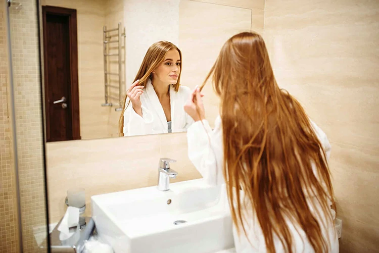 Woman in bathrobe against mirror in bathroom